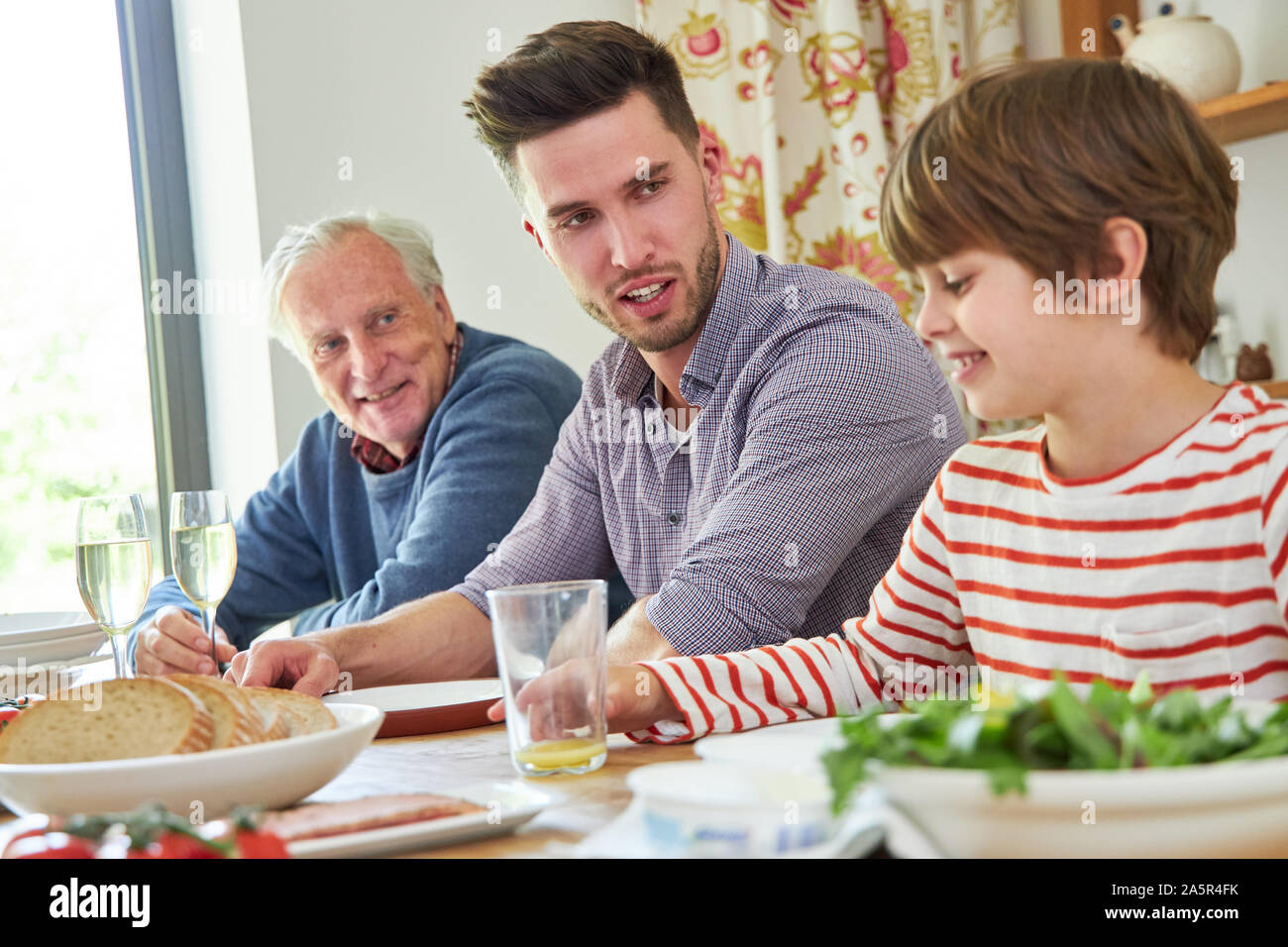 Familie mit Großvater und Enkel zu Mittag zusammen am Esstisch Stockfoto