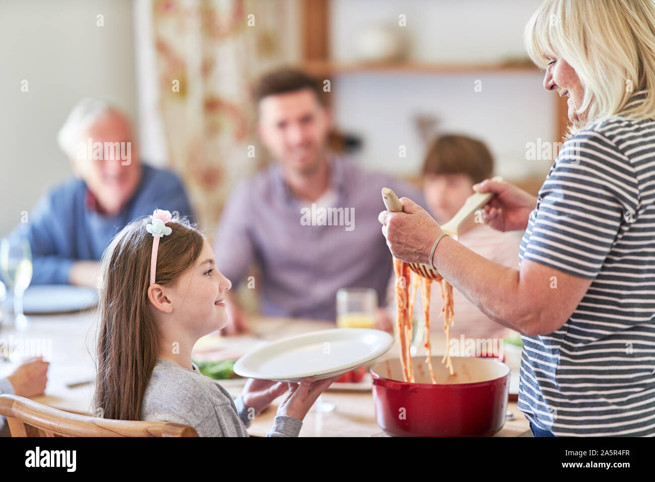 Großmutter vertreibt eine Portion Spaghetti zum Mittagessen zu Enkelkind Stockfoto