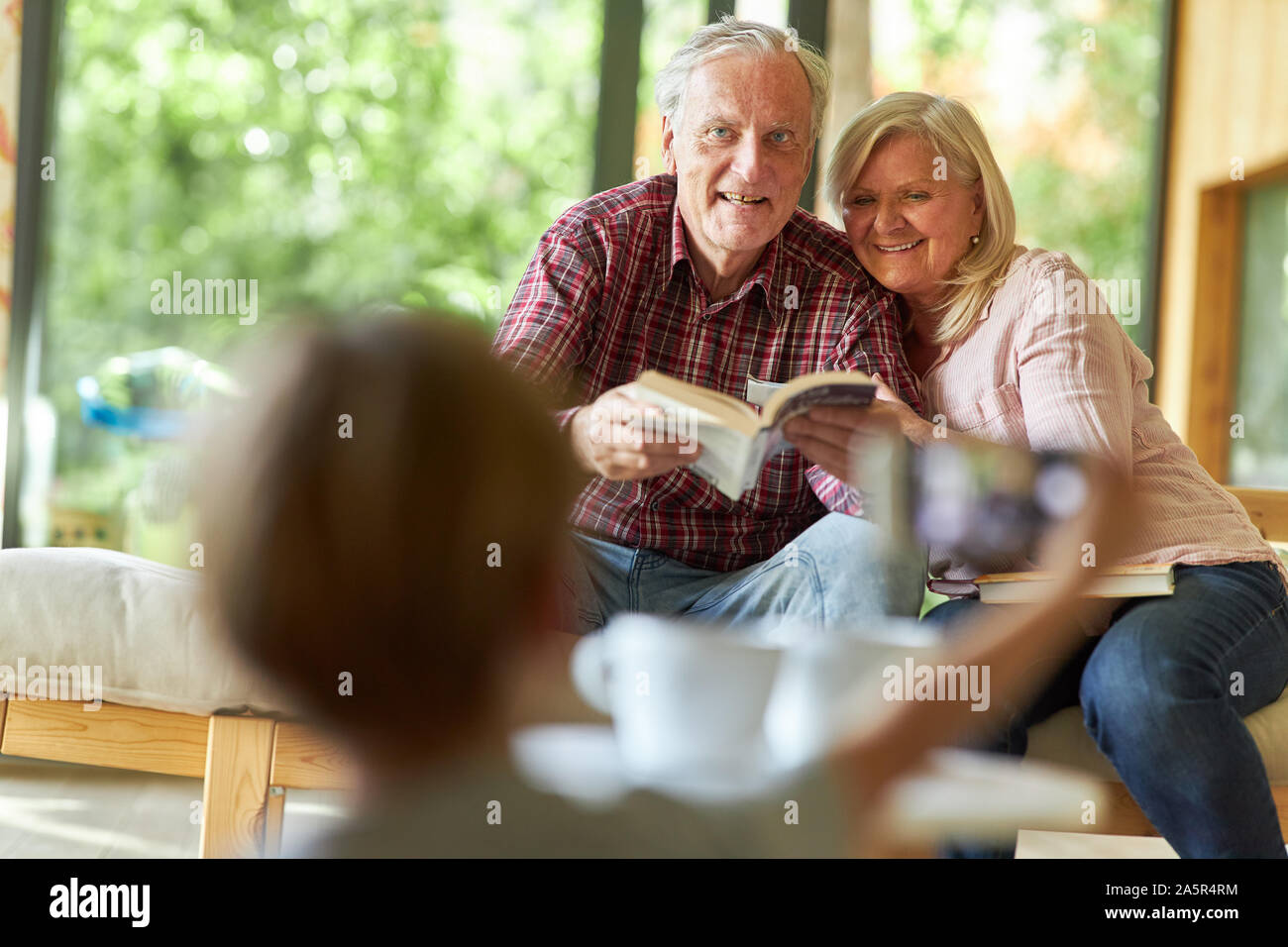 Enkelkind fotografiert seine Großeltern im Wohnzimmer als Erinnerung Stockfoto