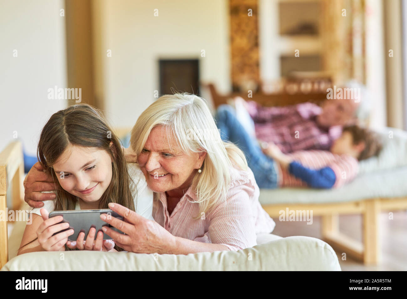 Großmutter und Enkel kind Blick auf einem Smartphone zu Hause zusammen Stockfoto