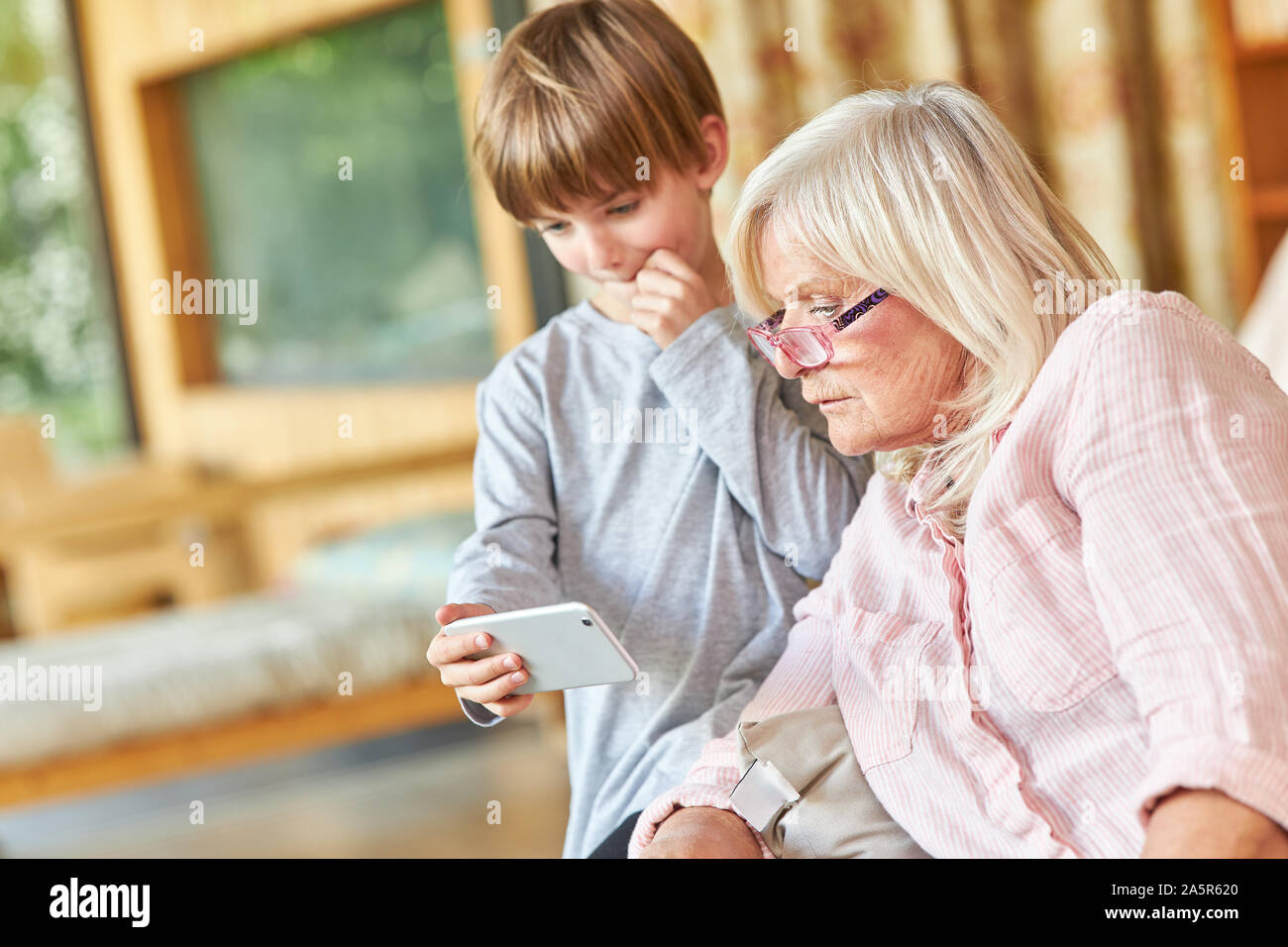 Großmutter und Enkel gemeinsam gelesen eine SMS-Nachricht auf dem Smartphone Stockfoto