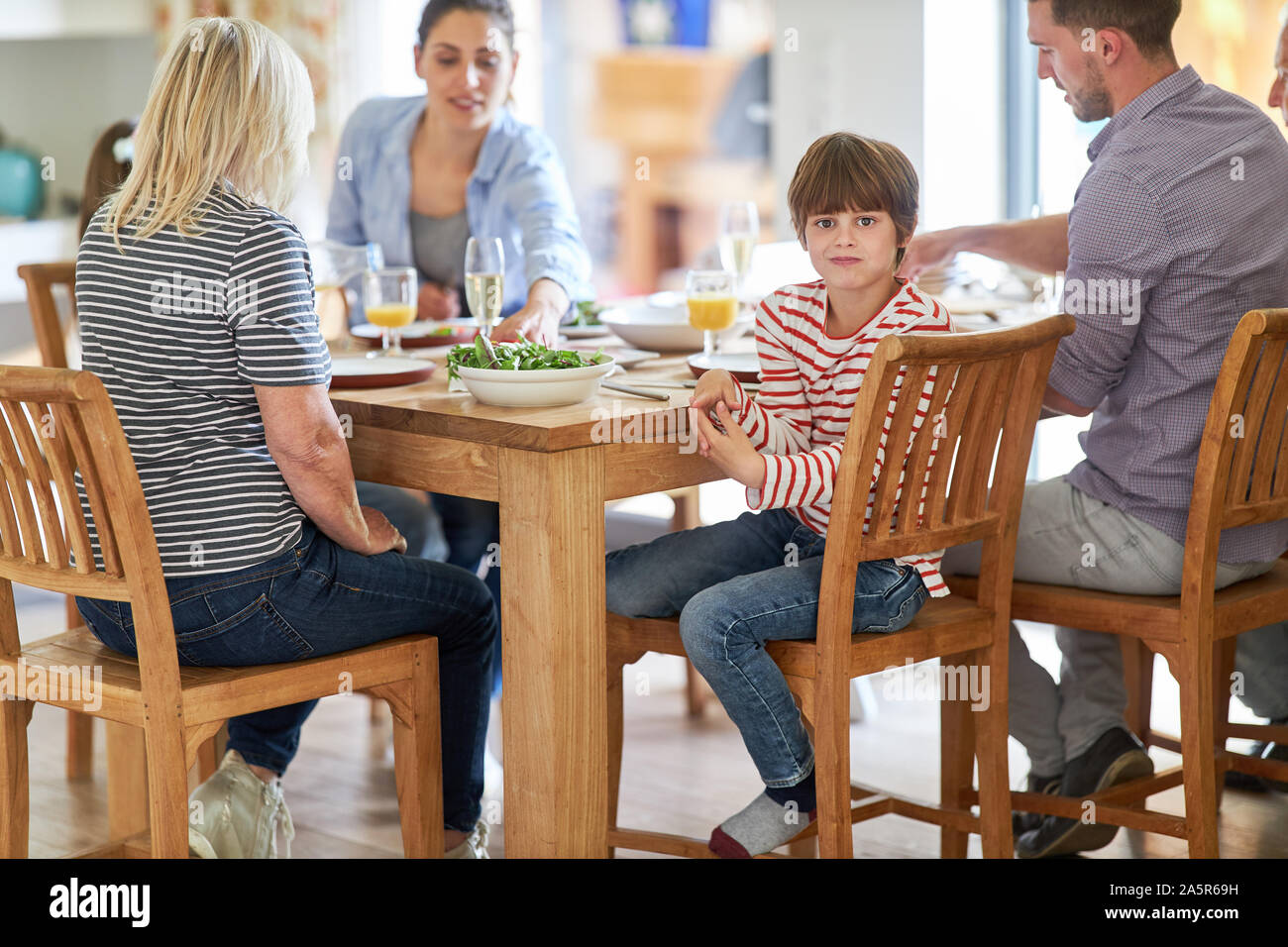 Junge am Esstisch beim Mittagessen mit Eltern und Großeltern gelangweilt Stockfoto