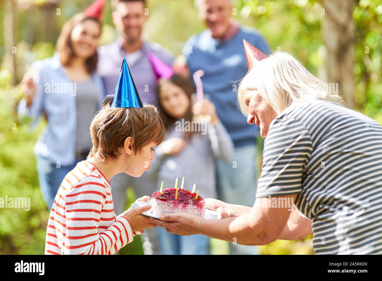 Geburtstag Kind bläst die Kerzen auf der Geburtstagstorte auf Feier im Garten Stockfoto