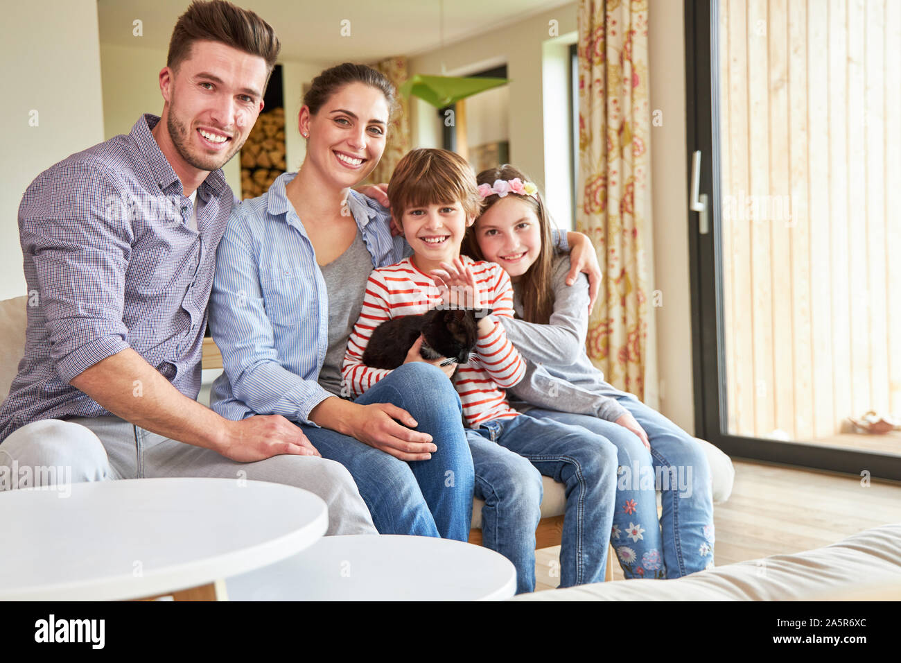 Glückliche Familie mit zwei Kindern und Katze zusammen im Wohnzimmer Stockfoto