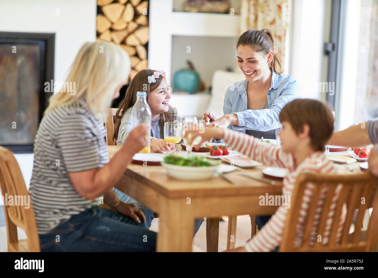 Mutter mit Kindern und Oma in Mittag- oder Abendessen am Esstisch Stockfoto