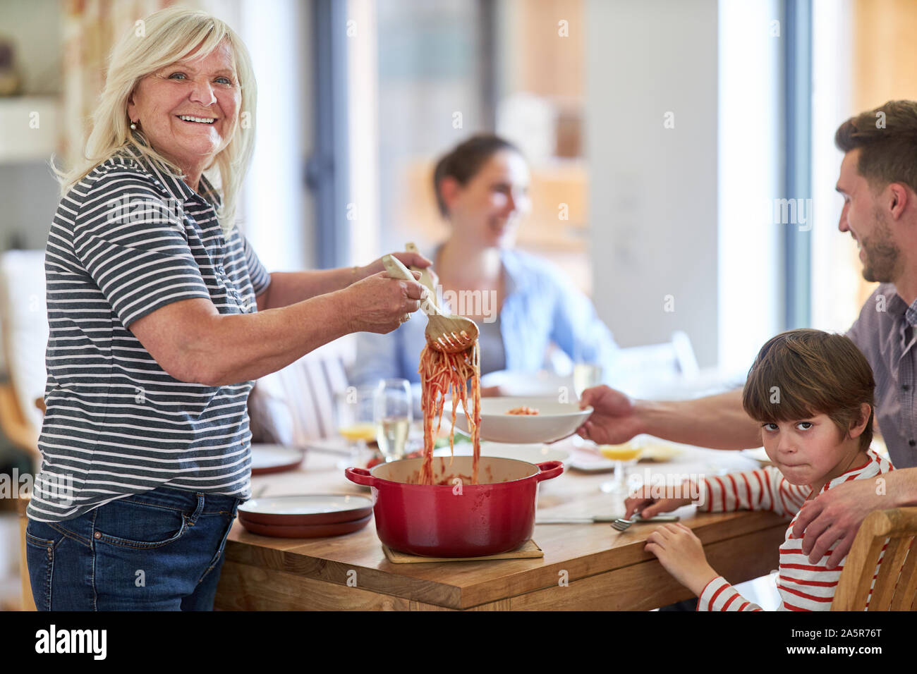 Oma am Esstisch spaghetti Verbreitung beim Mittagessen mit der Familie Stockfoto