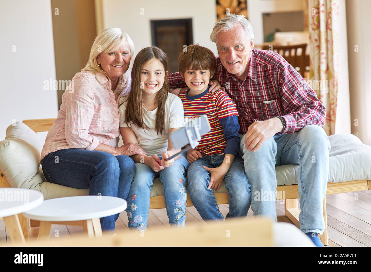 Enkel und Großeltern nehmen eine selfie mit selfie Stick im Wohnzimmer Stockfoto
