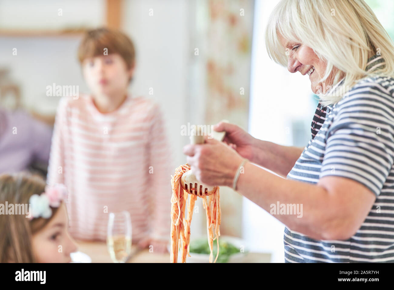 Großmutter mit Enkel Kinder Spaghetti zum Mittag- oder Abendessen Stockfoto