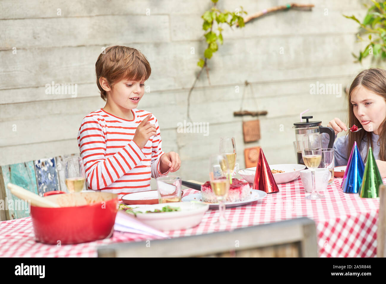 Zwei Kinder gemeinsam am Tisch in Essen auf einem Sommerfest im Garten Stockfoto