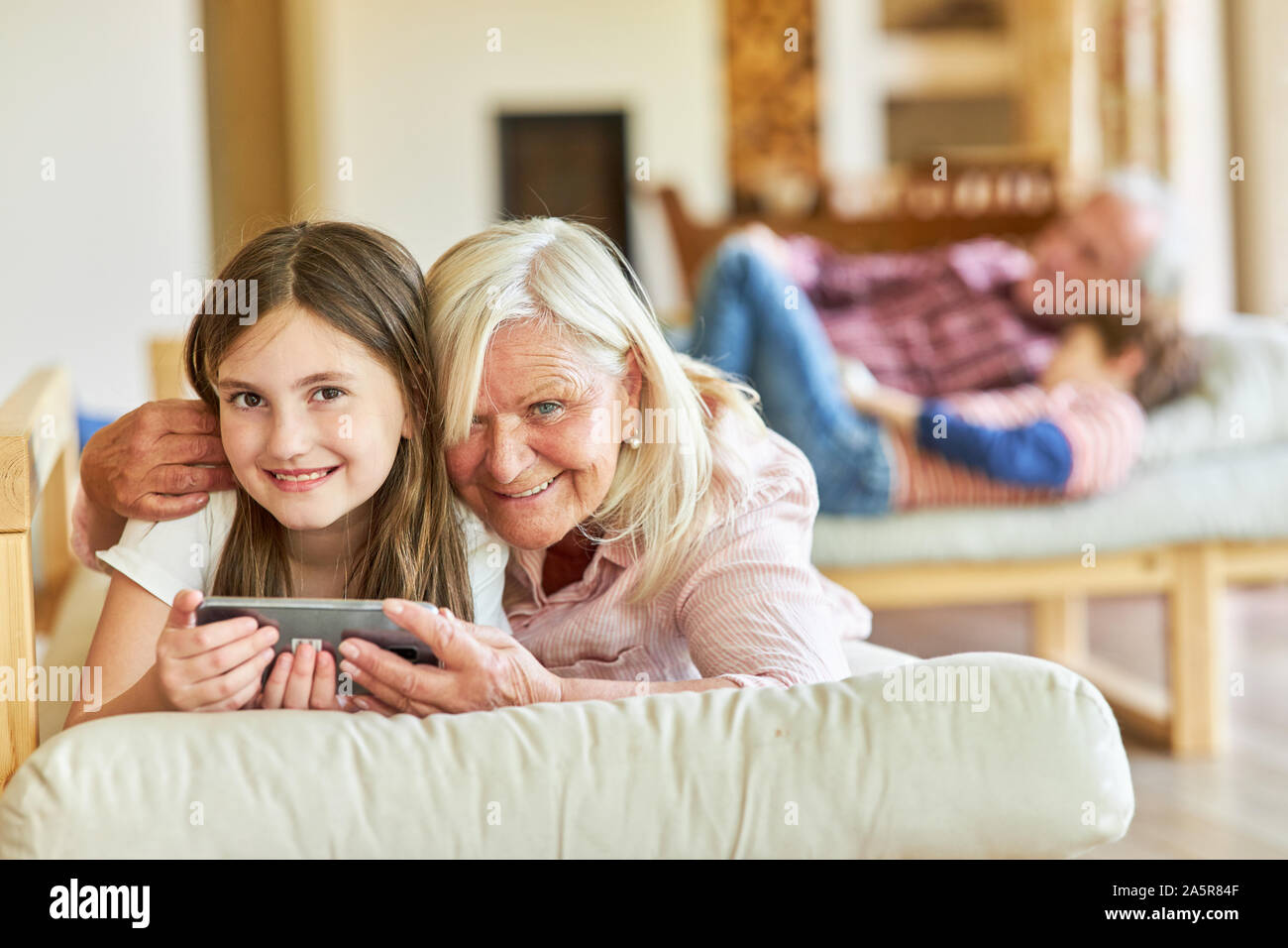 Glückliche Oma und Enkel Tochter im Wohnzimmer mit einem Smartphone Stockfoto