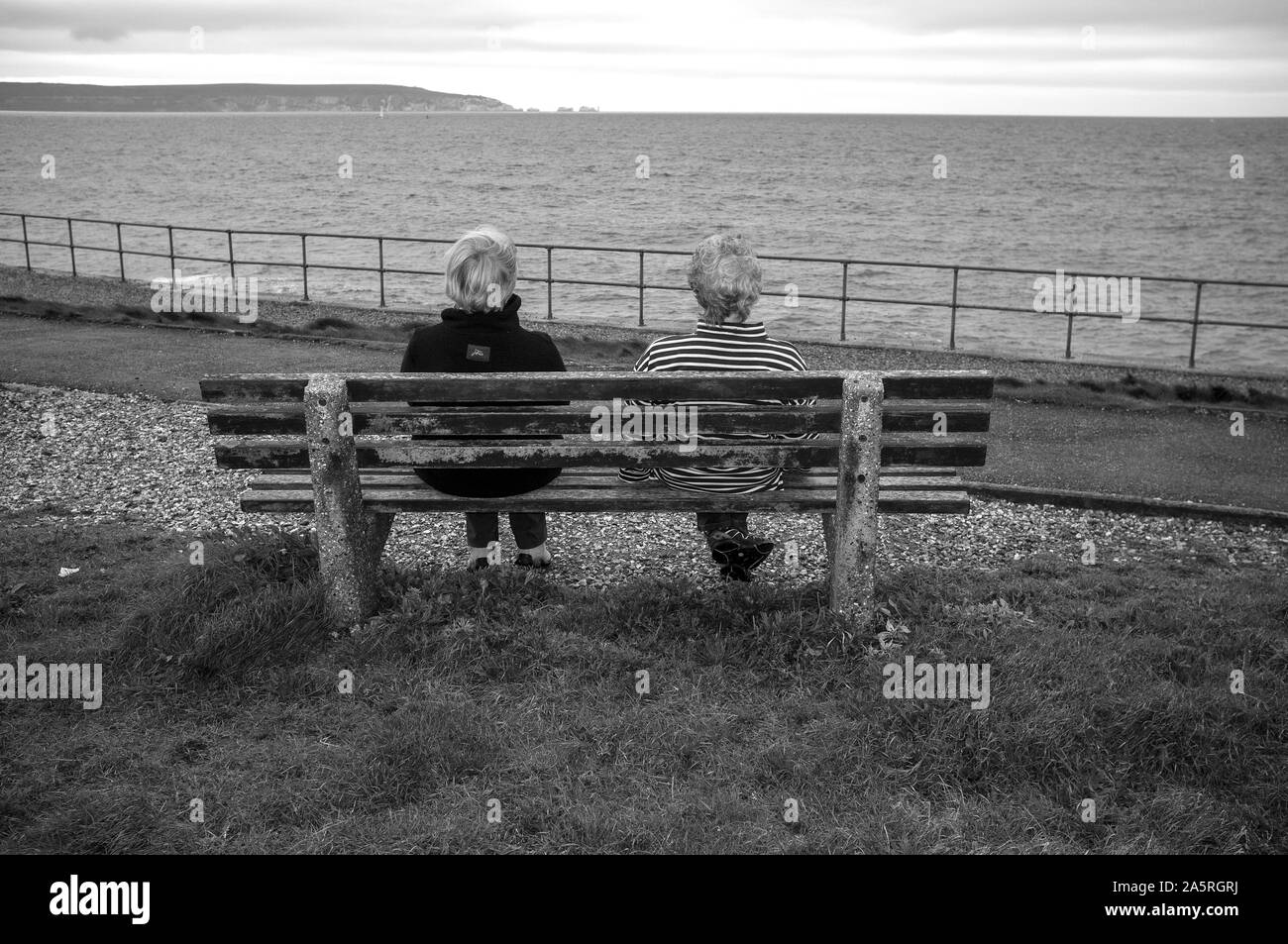 Zwei Damen sitzen auf einer Bank mit Blick auf das Meer. Stockfoto