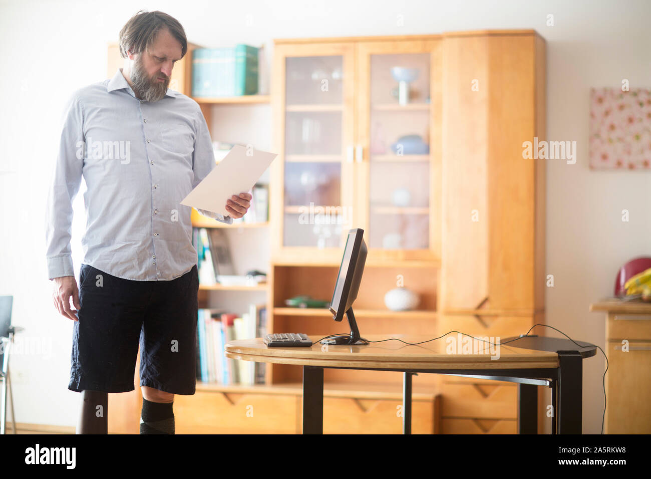 Älterer Mann mit Beinprothese zu Hause arbeiten mit Laptop