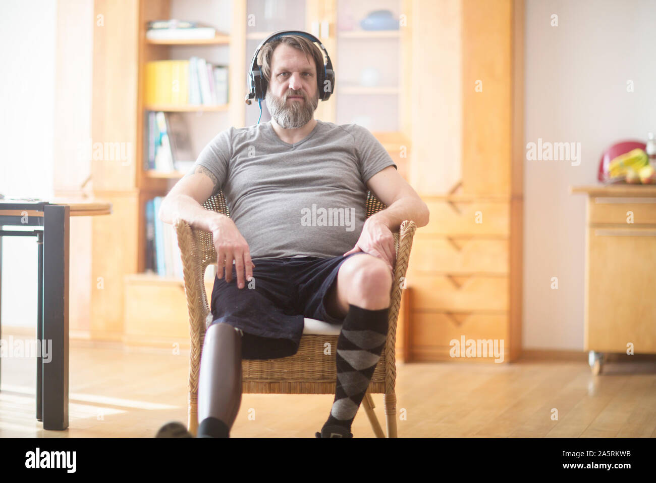 Älterer Mann mit beinprothese Hören von Musik in einem Stuhl Stockfoto