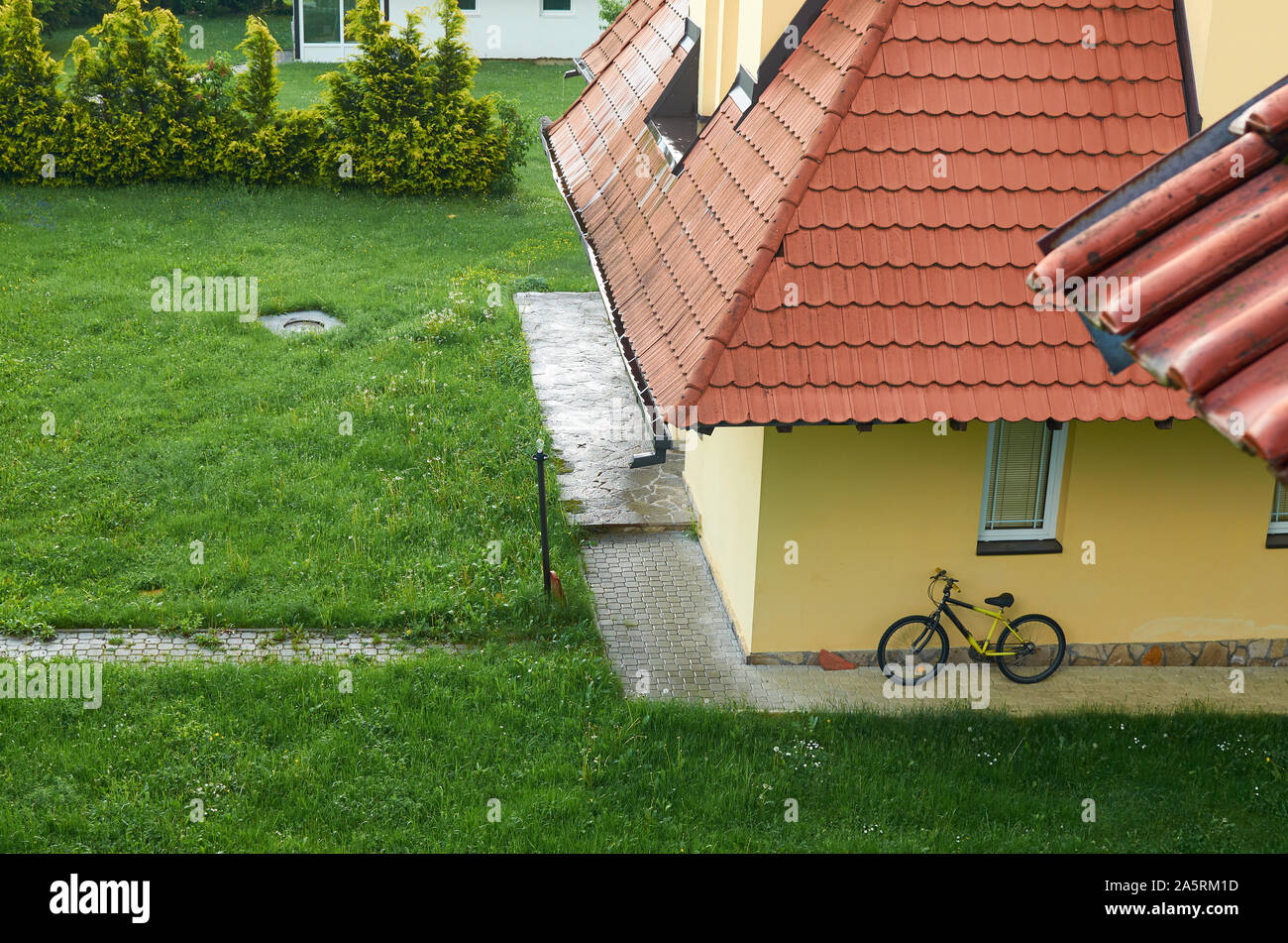 Hinterhof mit einem grünen Rasen und ein Fahrrad auf einem Haus Wand lehnte Stockfoto