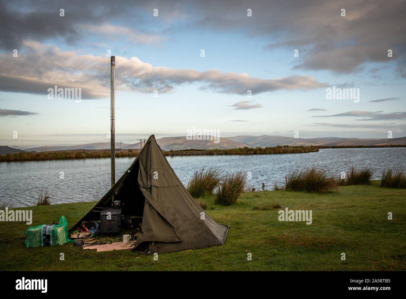 Wilding camping, Zelt mit Holz Feuer Herd neben einem See in Brecon Beacons, Wales UK Stockfoto