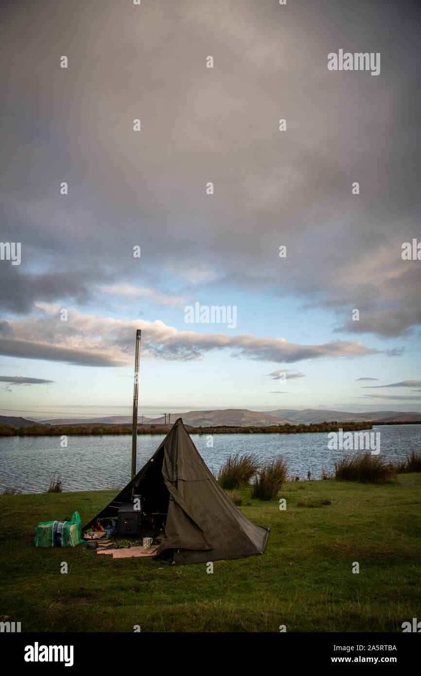 Wilding camping, Zelt mit Holz Feuer Herd neben einem See in Brecon Beacons, Wales UK Stockfoto