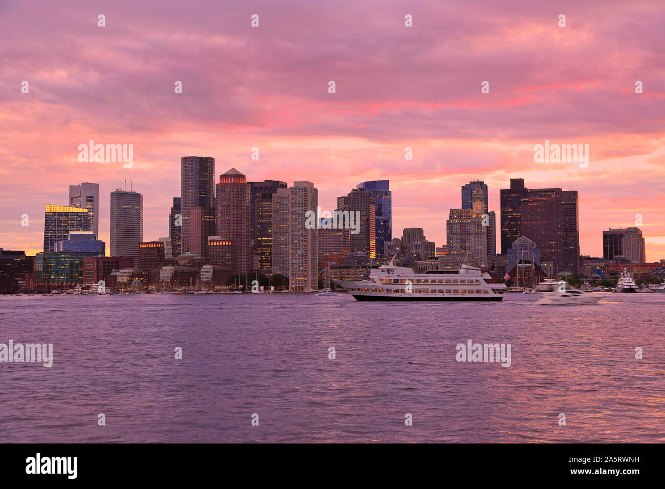 Boston Skyline bei Sonnenuntergang mit Boot segeln im Vordergrund, USA Stockfoto