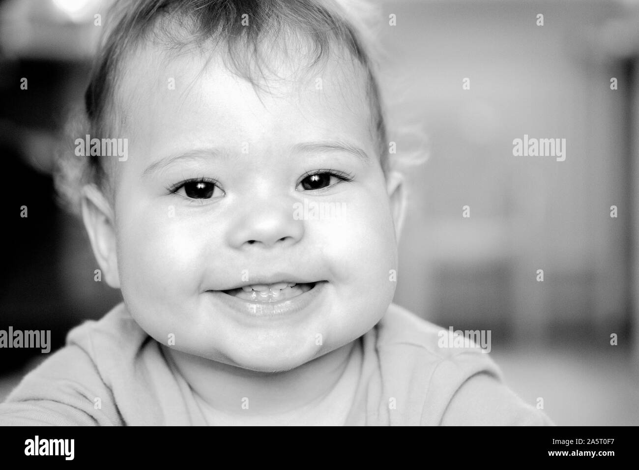 Junge Mädchen baby Schwarz und Weiß portrait. Glücklich lächelnde Kind Kleinkind Porträt, Kaukasier, Nahaufnahme. 1 Jahr altes Baby, 4 Zähne im Mund Stockfoto