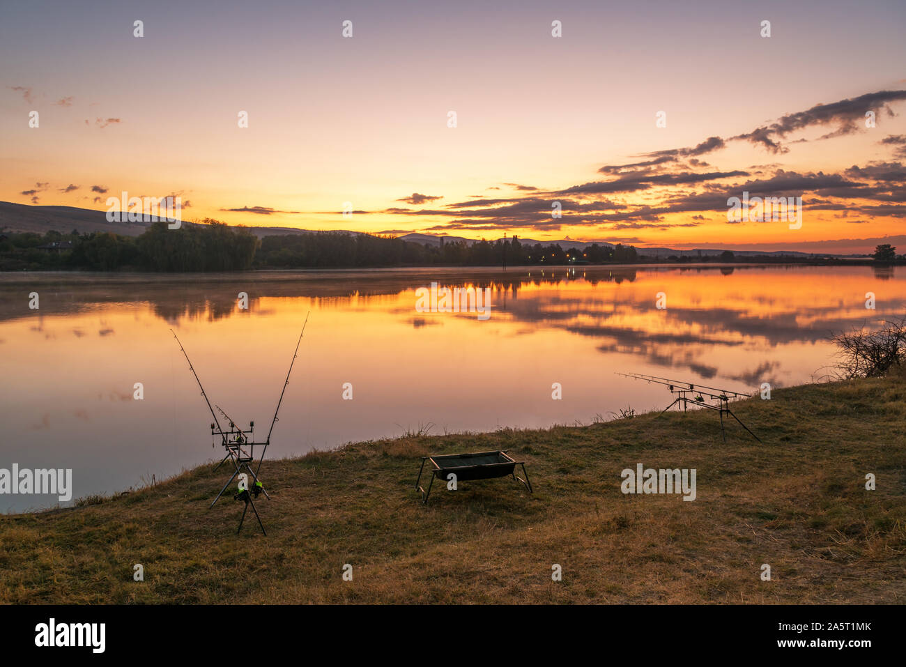 Karpfen angeln karpfen beißen Indikatoren und Rollen auf rod pod in der Nähe des Flusses. Angeln bei Sonnenaufgang. Stockfoto