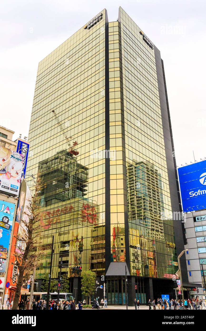 Japan, Tokio. Die Sumitomo Fudosan Akihabara Gebäude überragt die Fußgänger auf der Straße, den anderen in seinen Fenstern reflektiert. Stockfoto