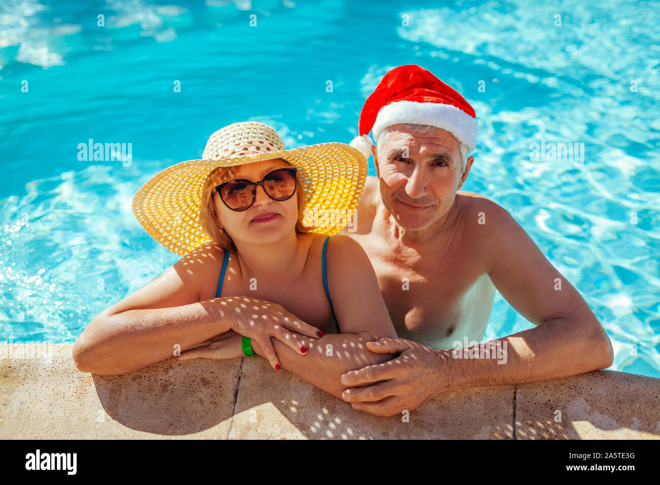Neues Jahr und Weihnachten feiern. Mann in Santa's Hut und Frau entspannen im Pool. Tropischer Urlaub Familienurlaub Stockfoto Neues Jahr und Weihnachten feiern. Mann in Santa's Hut und Frau entspannen im Pool. Tropischer Urlaub Familienurlaub Stockfoto