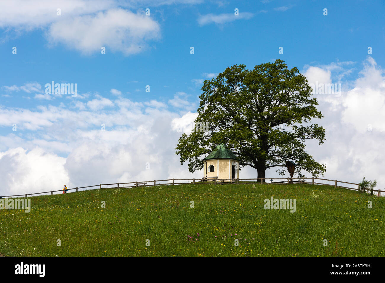 Kleinen bayerischen Kapelle auf einem Hügel mit Baum mit bewölktem Himmel im Hintergrund Stockfoto