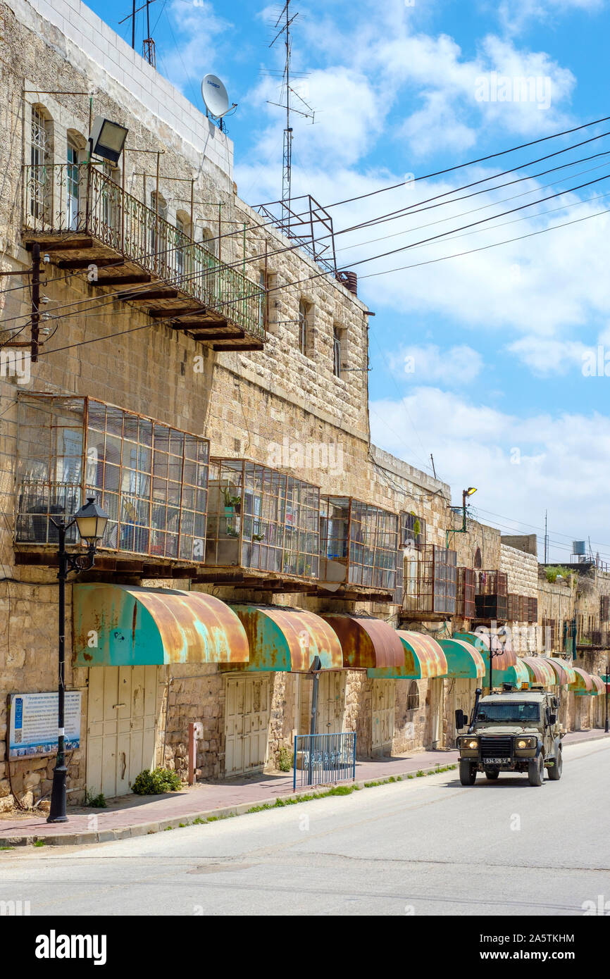 Ein israelisches gepanzertes Fahrzeug verläuft vor leeren Geschäfte und Gebäude auf Shuhada Street, die für Palästinenser geschlossen ist. Hebron (al-Khalil), West B Stockfoto