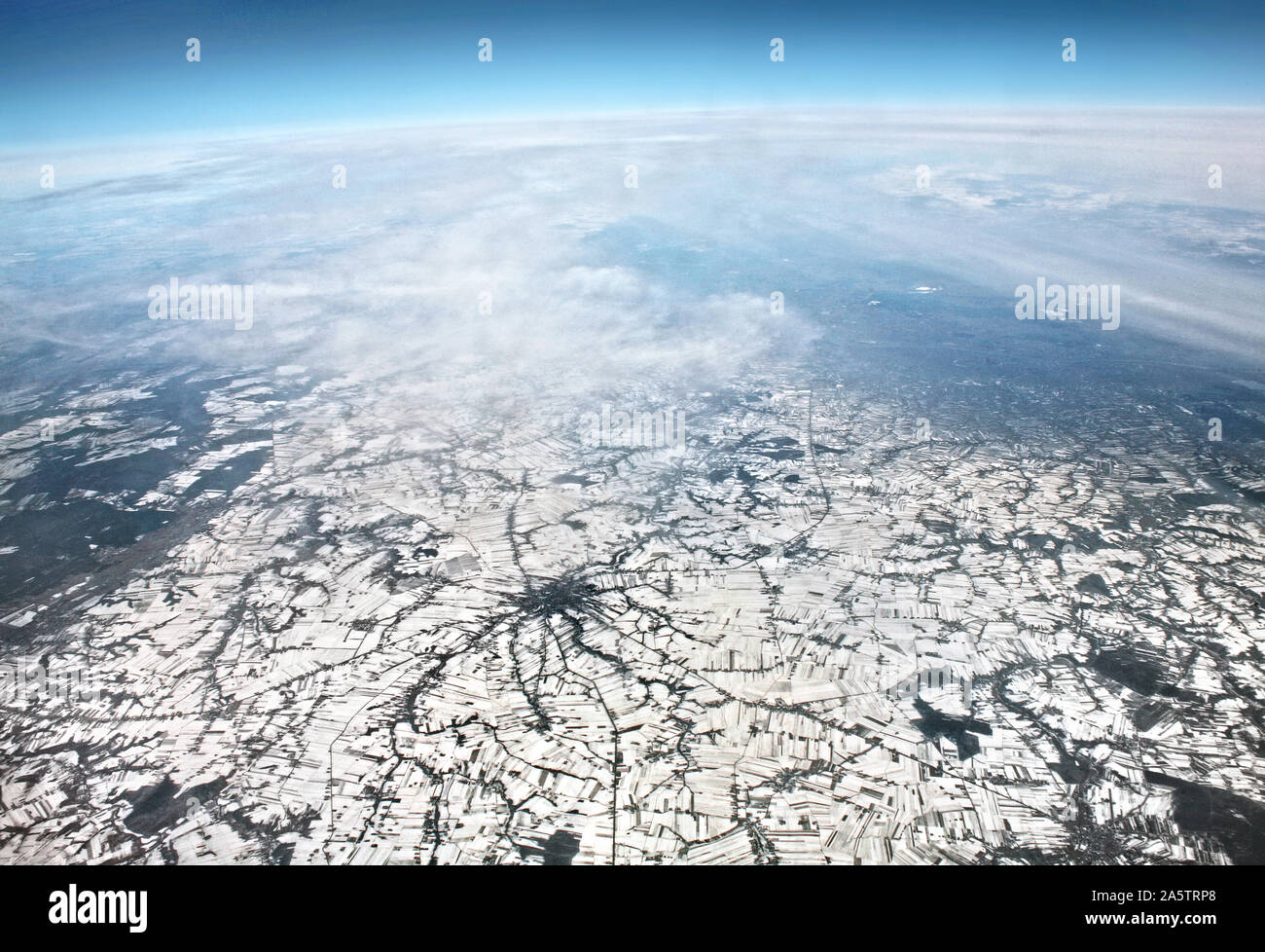 Ein Teil der auf der Erde. Luftbild von der Erde aus mit Horizont. Blick vom Flugzeug auf Winter. Europa von oben mit Teil von Himmel und Wolken. Stockfoto