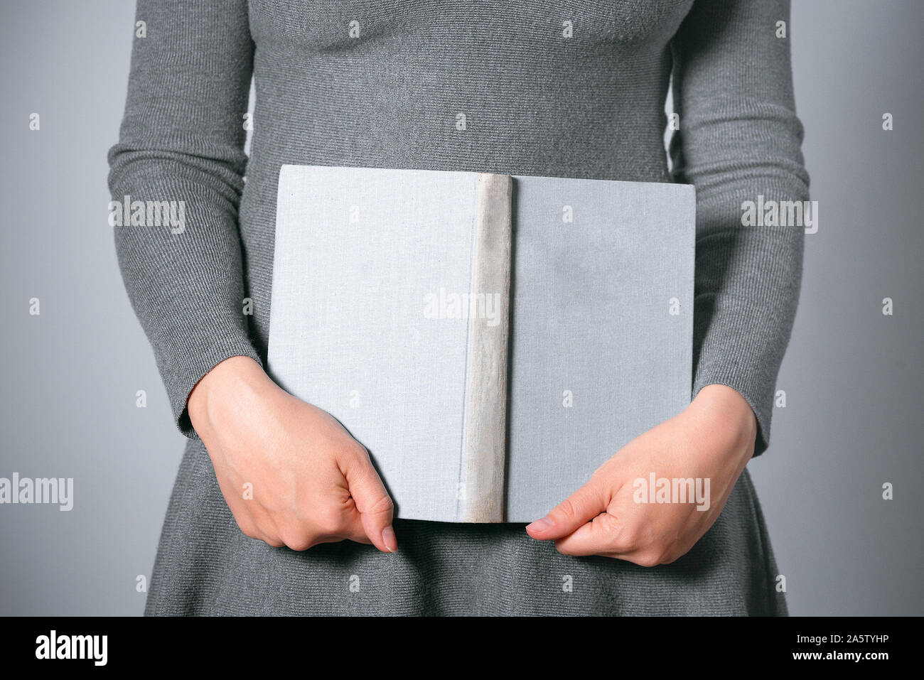 Frau mit offenem Buch in den Händen auf grauem Hintergrund. Stockfoto