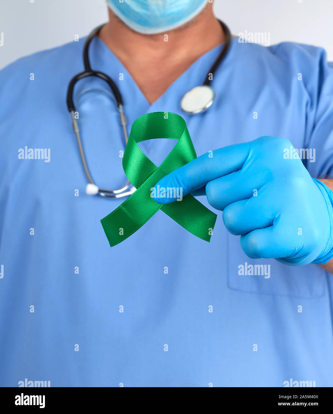 Arzt in der blauen Uniform und Latex Handschuhe hält eine grüne Schleife als Symbol der frühen Forschung und Seuchenbekämpfung, Symbol der Lyme Krankheit, Niere transp Stockfoto