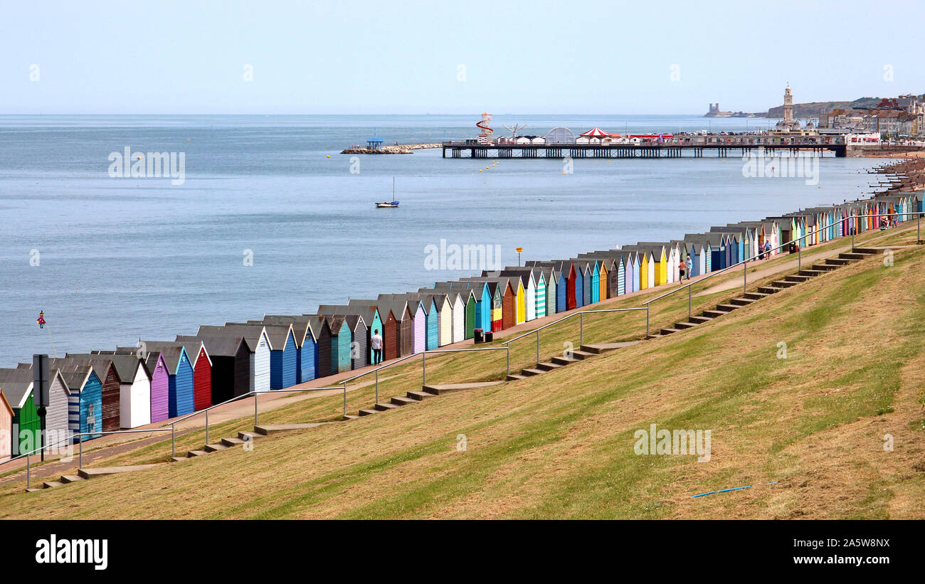 Blick von der Western Esplanade, Herne Bay von Dutzenden gayly lackiert Strand Hütten entlang der Strandpromenade. In der Nähe befindet sich der Glockenturm und die Pier. Stockfoto