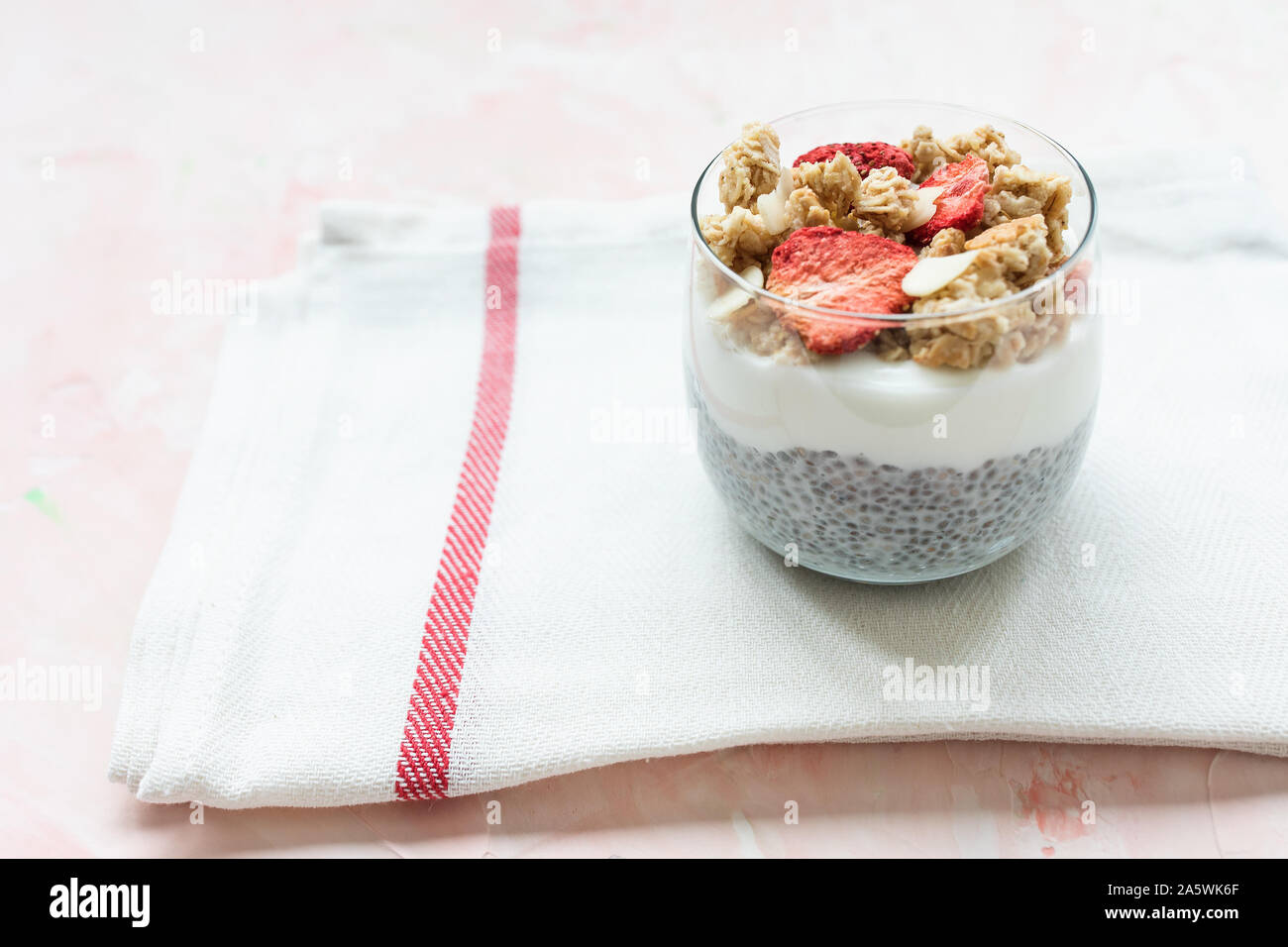 Über Nacht Chia Samen parfait Milchreis mit Mandeln Milch, Joghurt, hausgemachtes Müsli, getrocknete Erdbeeren und Mandeln in ein Glas. Superfood und veganes Essen co Stockfoto