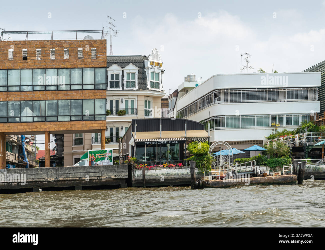 Die Stadt Bangkok, Thailand - 17. März 2019: Chao Phraya Fluss. Kleine Vivi der Kaffee Ort Gebäude unter größeren mit eigenen Landung entlang Quay, wi Stockfoto