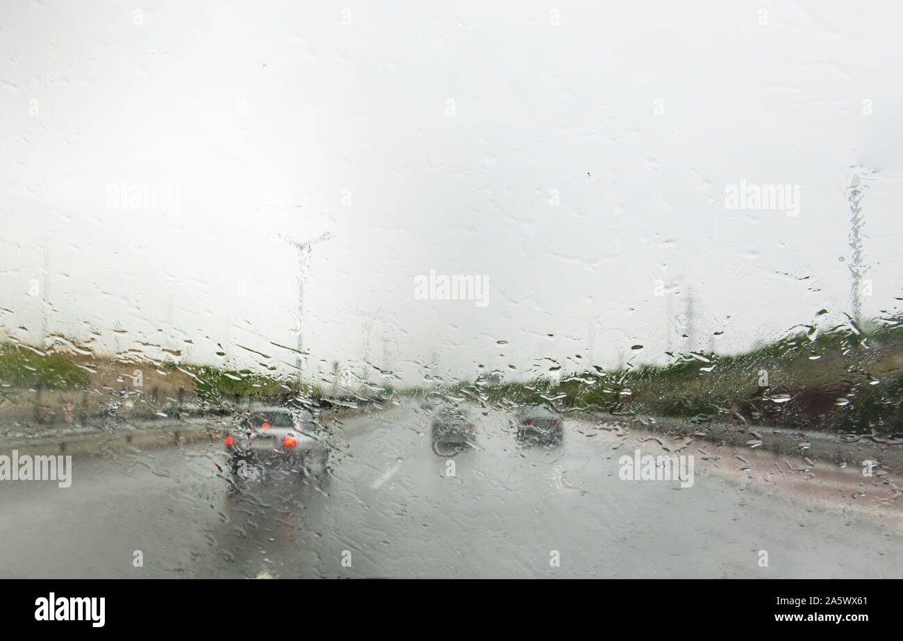 Ansicht vor unser Auto während der Fahrt auf der Autobahn im Regen mit dem Regentropfen auf der Windschutzscheibe. Stockfoto