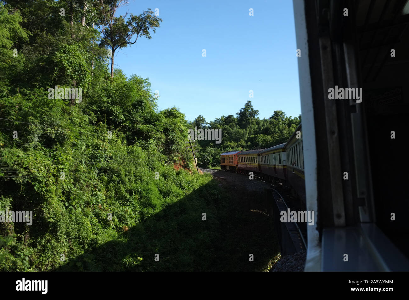 Blick aus dem Zug Bahn macht eine Kurve durch eine wunderschöne natürliche grüne Wiesen und Berge biegen. Reisen in Thailand Stockfoto