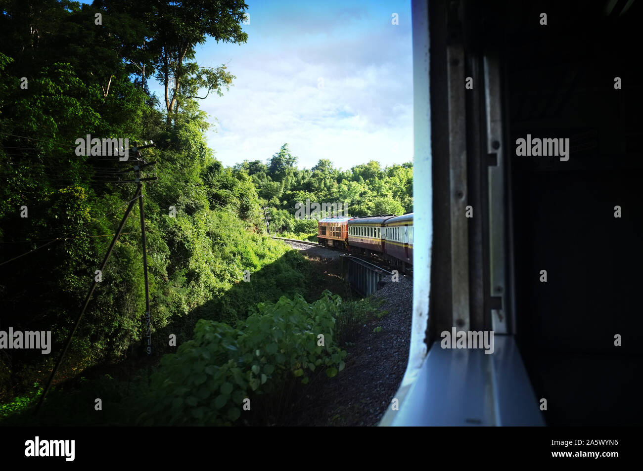 Blick aus dem Zug Bahn macht eine Kurve durch eine wunderschöne natürliche grüne Wiesen und Berge biegen. Reisen in Thailand Stockfoto