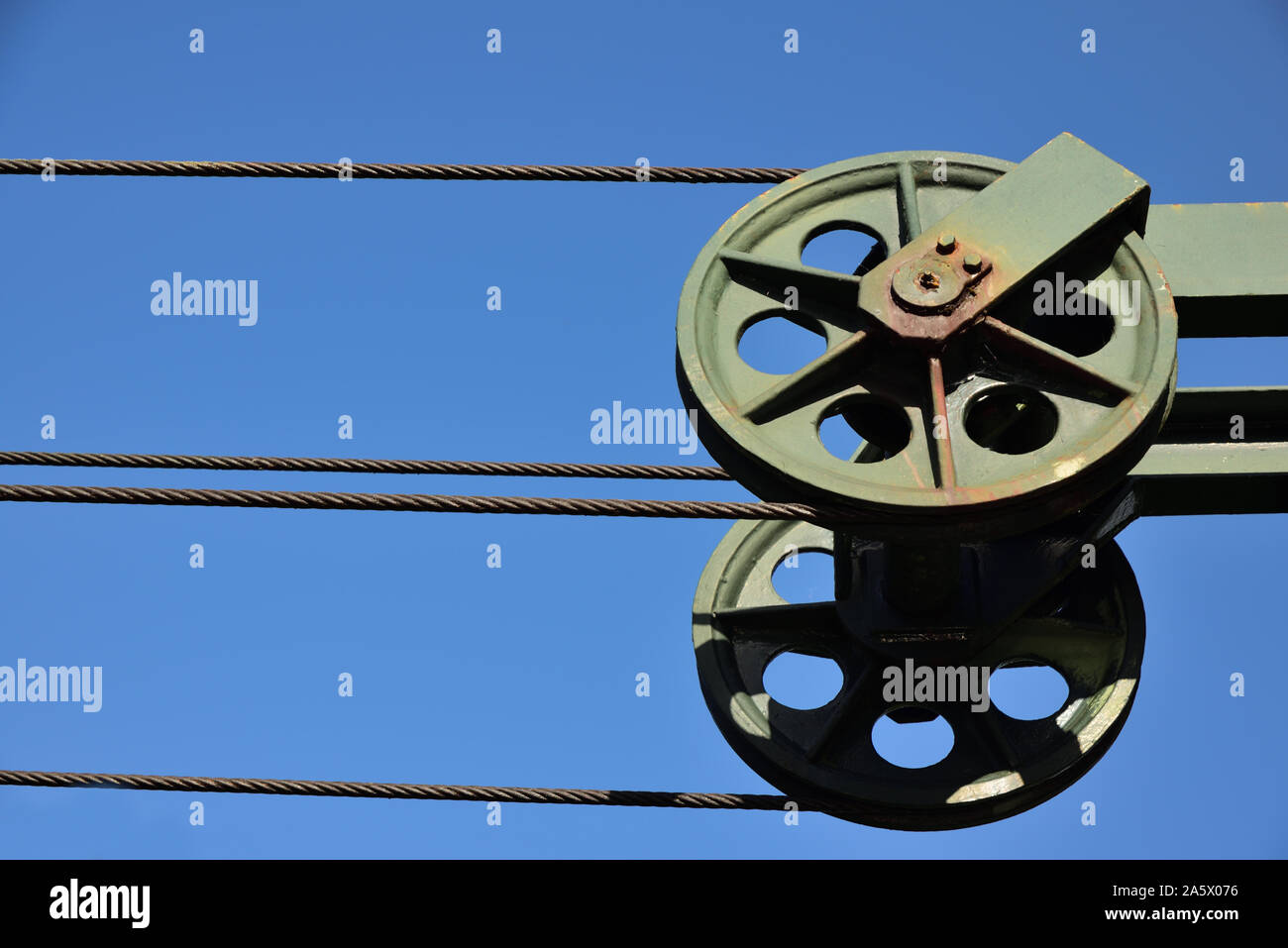 Rolling über Metall, ein Stahlseil erstreckt sich gegen einen blauen Himmel als Hintergrund Stockfoto
