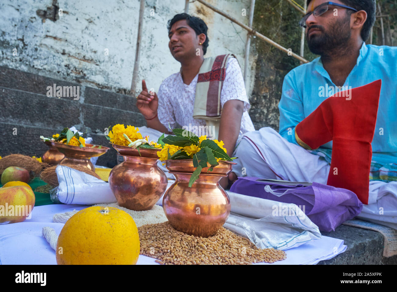 Ein hinduistischer Priester (l) an banganga Tank, Walkeshwar, Mumbai, Indien, mit Opfergaben vor, Riten, die zu Ehren eines Mannes (r) verstorbenen Verwandten Stockfoto