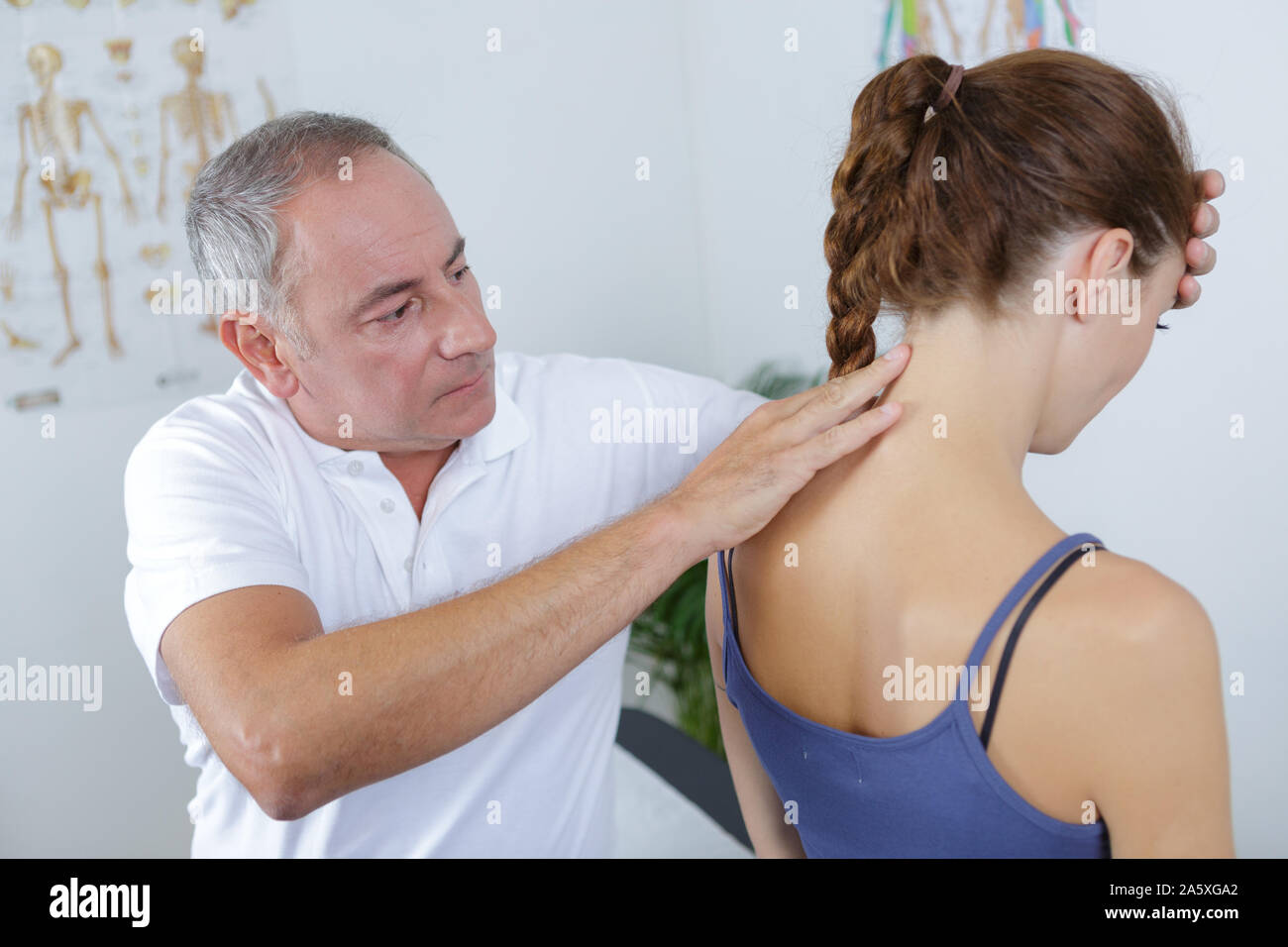 Männliche Physiotherapeuten auf junge weibliche Patienten zurück Stockfoto