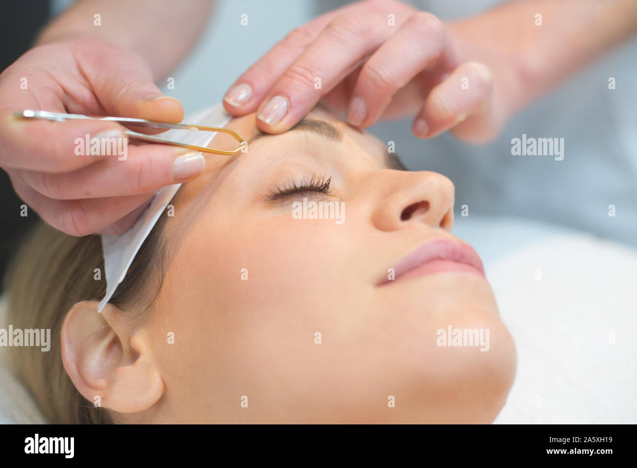 Kosmetikerin tut Augenbrauen einer Frau in Kosmetik Studio Stockfoto
