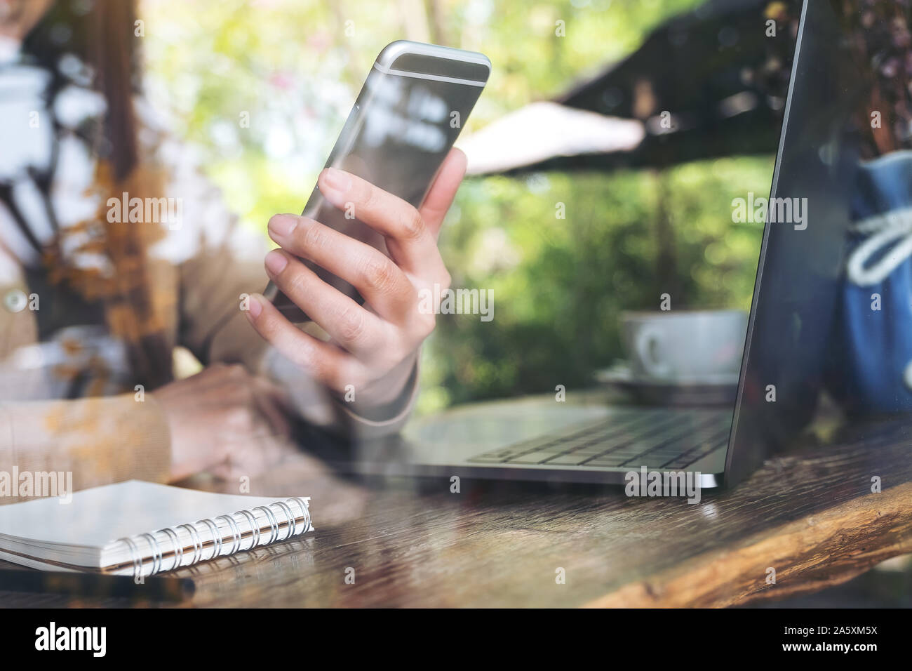 Closeup Bild der Frau Hand und Smart Phone, während mit Laptop im Cafe Stockfoto