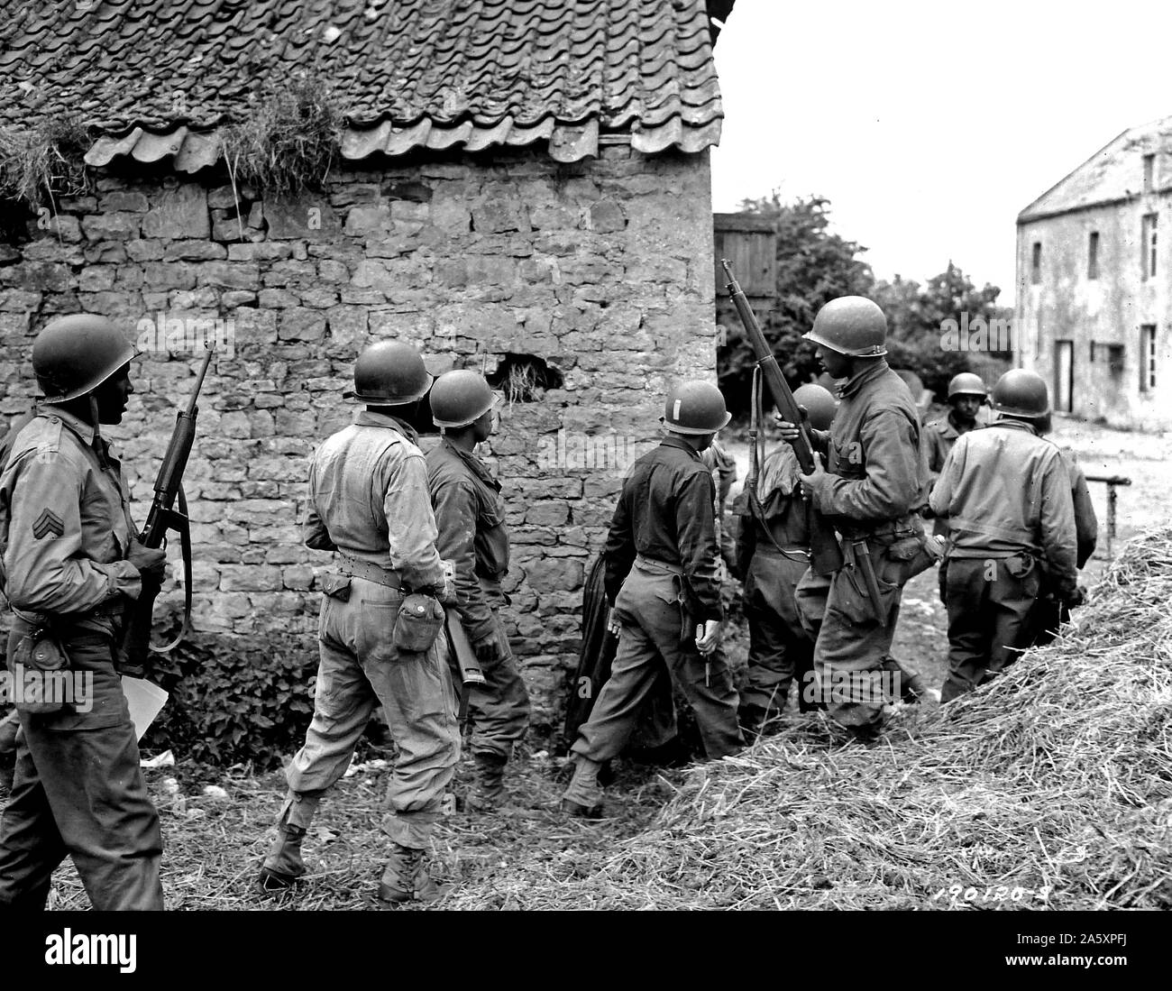 [ORIGINAL CAPTION] Invasion der Alliierten in Frankreich... Ein Trupp von Negro Truppen umgibt ein Haus in einer Stadt in Frankreich, die sich darauf vorbereiten, zu beseitigen, ein Deutscher Scharfschütze eine Vorauszahlung. 10. Juni 1944. Omaha Beachhead, in der Nähe der Vierville Sur-Mer, Frankreich Stockfoto