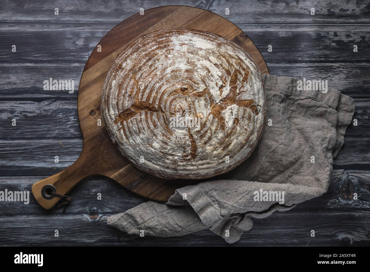 Hausgemachte organische Sauerteigbrot von oben, flach gesehen legen Perspektive. Die gebrochene Rustikales Brot ist auf einem hölzernen Schneidebrett gelegt, neben einem Leinen c Stockfoto