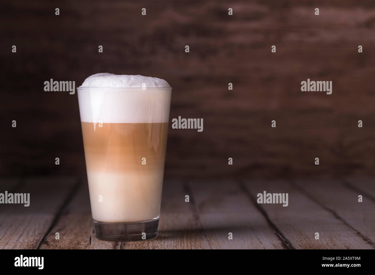 Kaffee Cafe Latte in einem hohen Glas auf einer hölzernen Hintergrund Macchiato. Es ist Kopieren Raum neben der Glas, und das Foto ist horizontal. Stockfoto