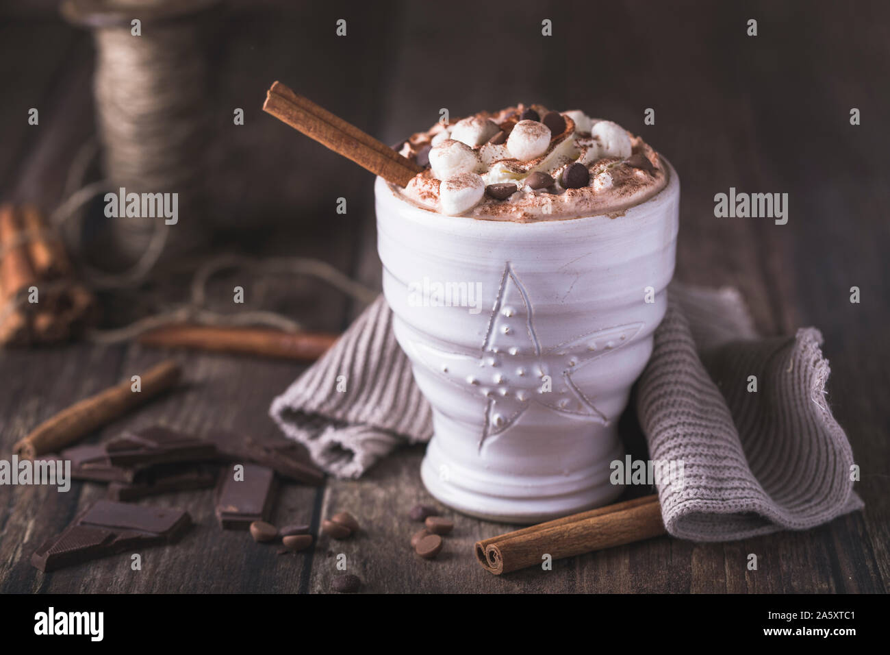Eine weiße Tasse mit luxuriösen Heiße Schokolade mit Sahne und Stücke von Marshmallows und Chocolate Chips. Stücke Schokolade sind rund um o verstreut Stockfoto
