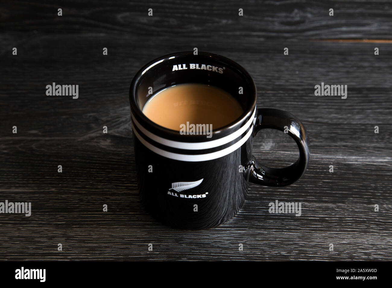 Tasse Tee in eine Alle schwarzen Schale gemacht. Alle Schwarzen sind eine der besten rugby Teams der Welt. Starker weißer Tee sitzen auf einem dunklen Holz. Stockfoto