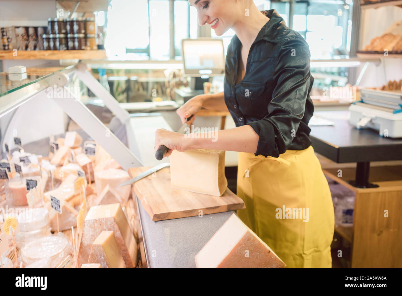 Junge shop Clerk in deli Schneiden von Käse Stockfoto