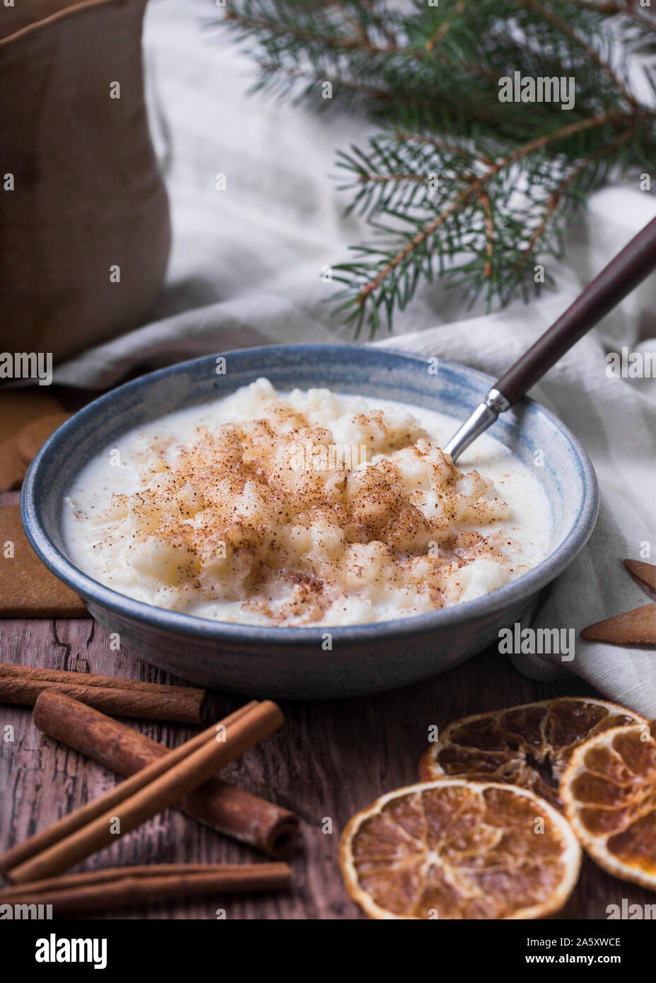 Traditionelle Milchreis auch als tomtegröt oder schwedische risgrynsgröt bekannt. Der Milchreis ist in einem blau Keramik Schüssel auf einen hölzernen Tisch, mit gingerbre Stockfoto