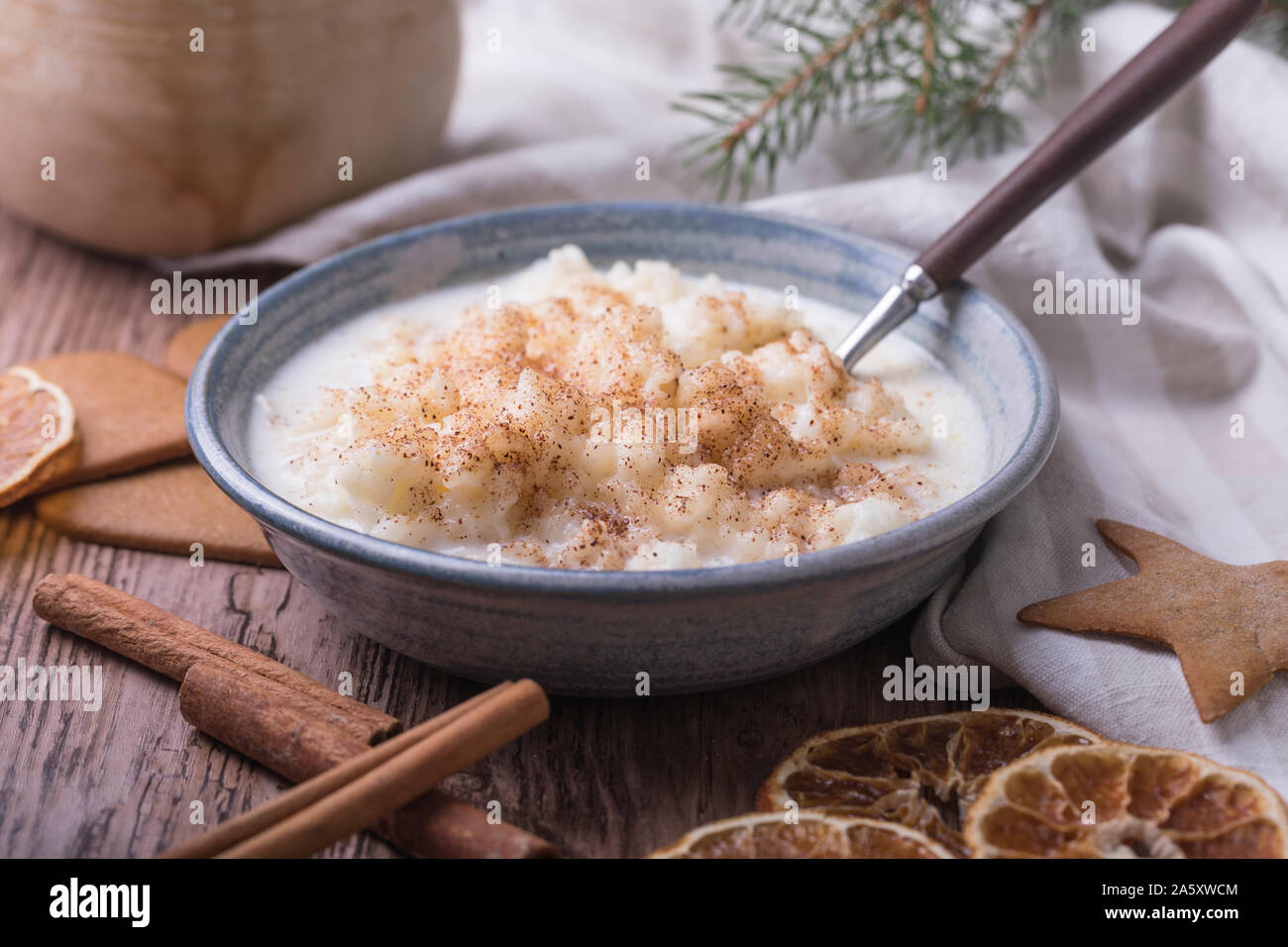 Traditionelle Milchreis auch als tomtegröt oder schwedische risgrynsgröt bekannt. Der Milchreis ist in einem blau Keramik Schüssel auf einen hölzernen Tisch, mit gingerbre Stockfoto