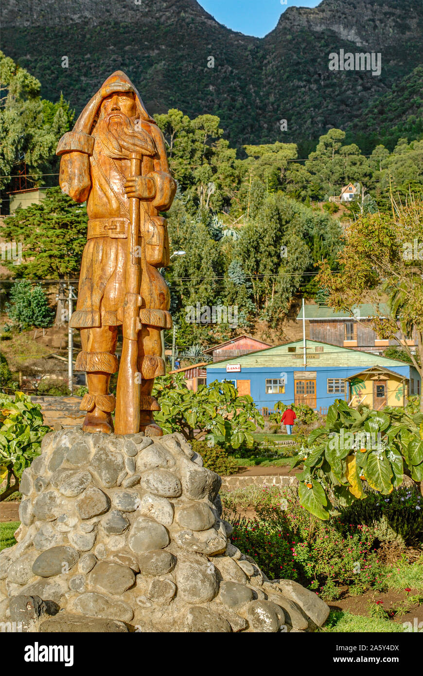 Robinson Crusoe-Statue auf der Juan-Fernandez-Insel mit der Besiedlung in den Hintergrund, vor dem Tsunami 2010, Chile Stockfoto